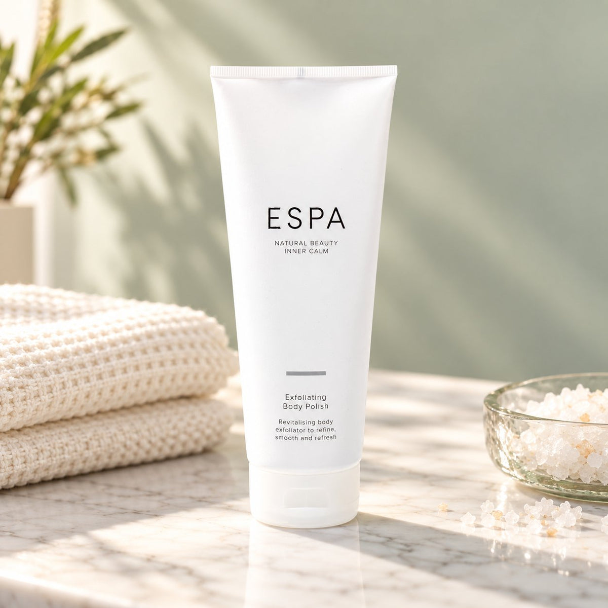 ESPA Exfoliating Body Polish on a marble counter beside a waffle towel (styled image)