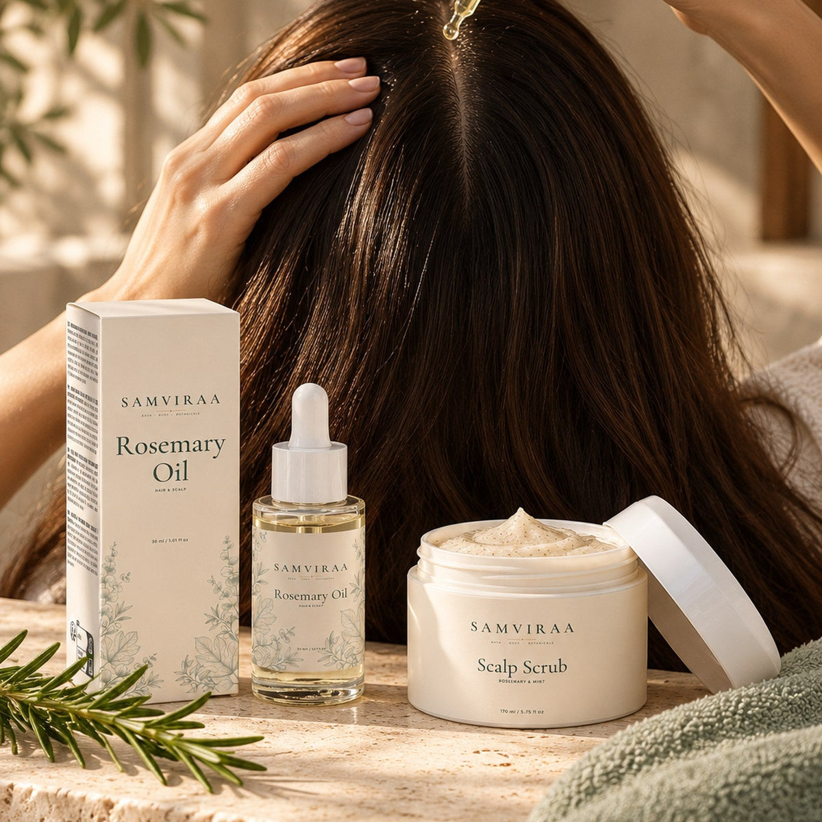 styled image: SAMVIRAA Rosemary Oil being added to a hair parting, with the Scalp Scrub on a travertine ledge