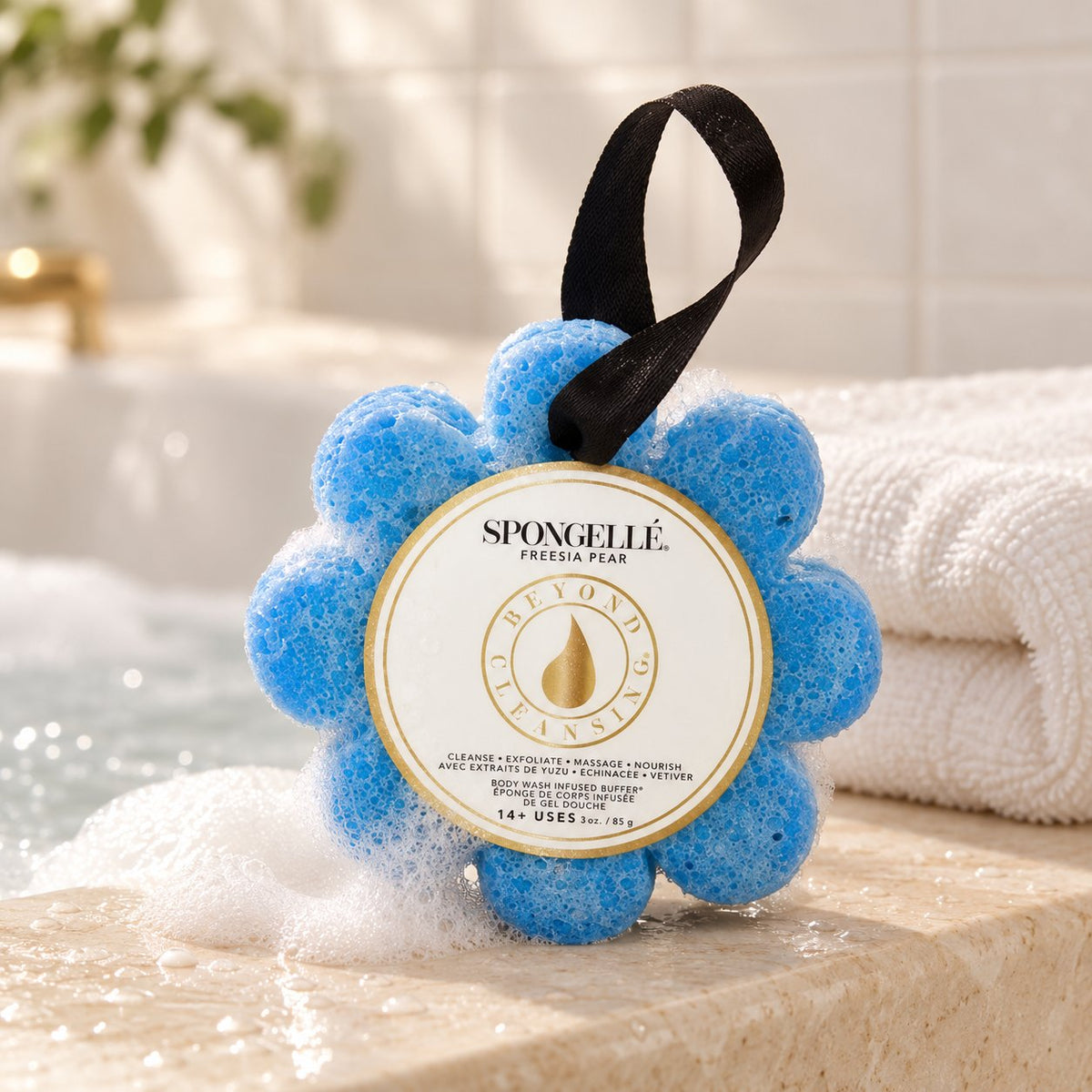 Spongelle daisy body buffer on the edge of a bath (styled image)