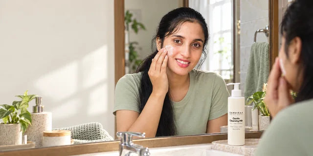 A woman applying SAMVIRAA Gentle Cleansing Milk to her cheek.