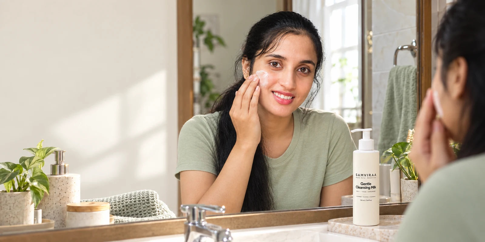 A woman applying SAMVIRAA Gentle Cleansing Milk to her cheek.